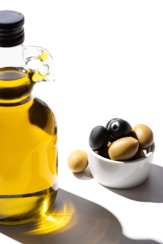olive oil in bottle near green and black olives in E5JAQC3 1 scaled