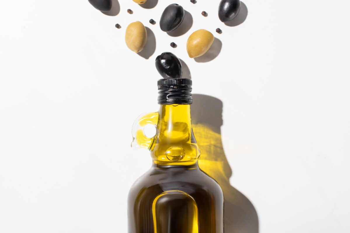 olive oil in bottle near green and black olives an 4VNYKPE